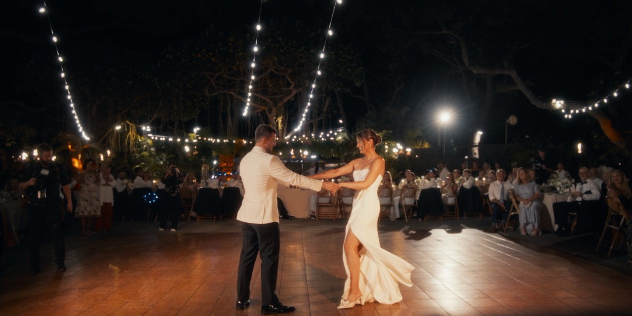 Caroline and Dylan dance together beneath the reception lights.