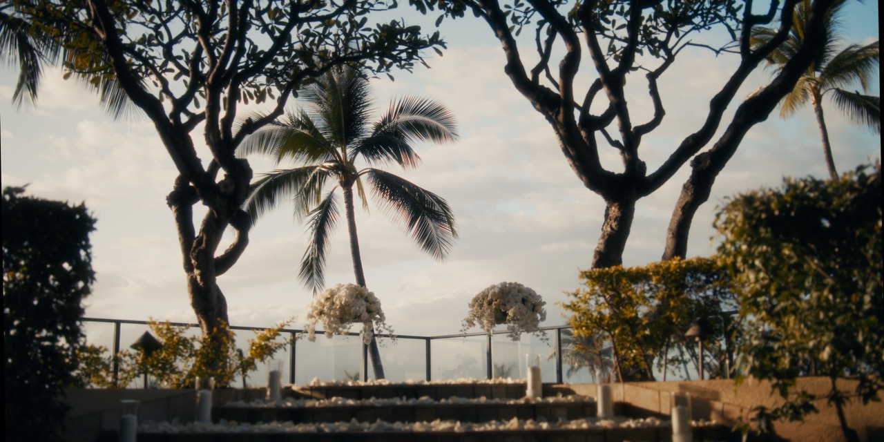 Empty Plumeria Point altar beneath mature plumeria trees with the ocean beyond