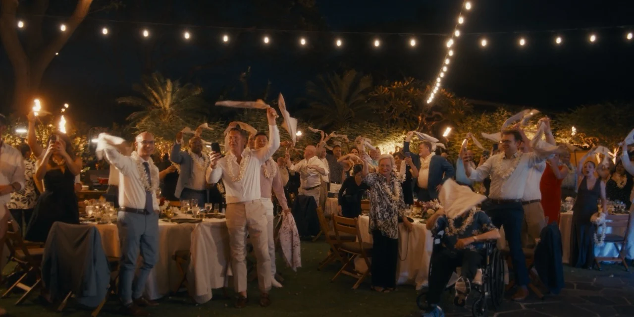 Guests raise their arms beneath string lights at the nighttime reception.